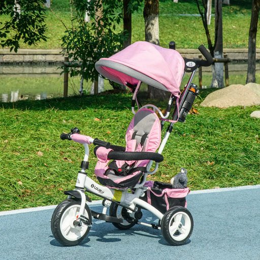 Pink and gray baby tricycle with canopy in a park setting