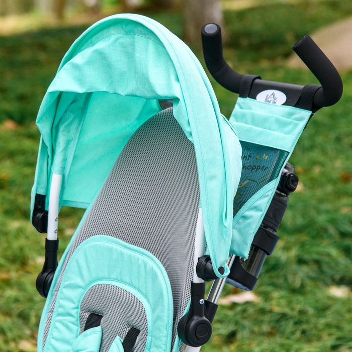 Turquoise and gray stroller with canopy in a grassy outdoor setting