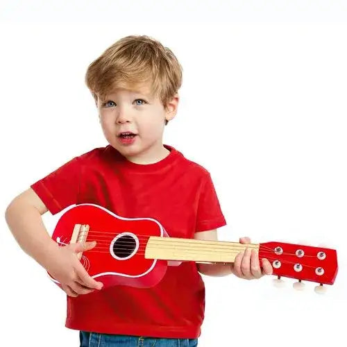 Young child in red shirt playing a red 6-string kids acoustic guitar on white background