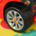 Close-up of toy car wheel from red kids engine toy set on colorful play mat