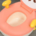 Children's potty chair with pink seat and yellow handles on a gray surface