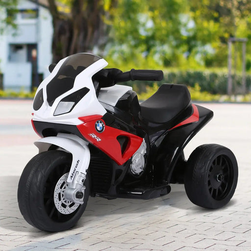 BMW red and white electric kids ride-on tricycle with black seat on outdoor pavement