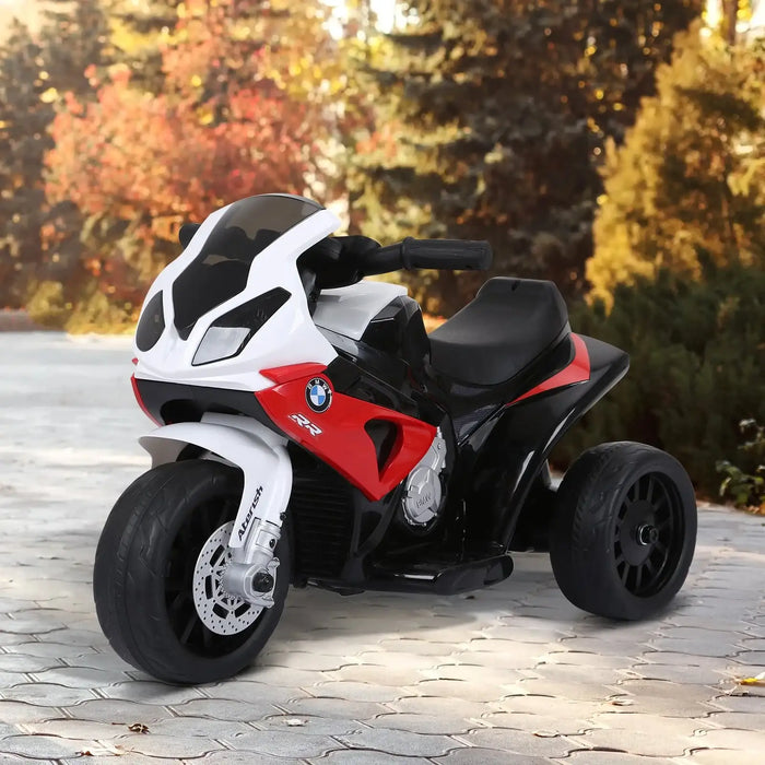 BMW RR children’s electric three-wheeler bike in red, white, and black on paved path with autumn foliage