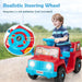 Young boy riding red and blue battery-powered toy jeep with realistic steering wheel outdoors