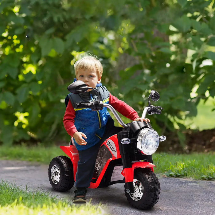 Child playing with a red toy motorcycle outdoors