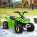 Green kids electric quad bike with black wheels on sand in a playground setting