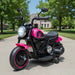 Pink kids electric ride-on motorbike with training wheels outdoors on driveway