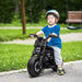 Child riding 6V kids electric police motorcycle with siren and training wheels outdoors