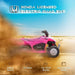 Pink Honda licensed kids electric quad bike rides in sandy desert with dust and blue sky.