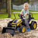 Child riding yellow 6V kids ride-on bulldozer toy with working shovel in sandbox