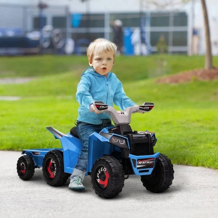 Toddler riding blue 6V kids ride-on quad bike with trailer outdoors on grass