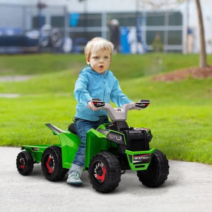 Child riding green kids 6V quad bike with trailer outdoors on grass
