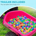 Pink kids ride-on quad bike trailer filled with colorful plastic balls on grass