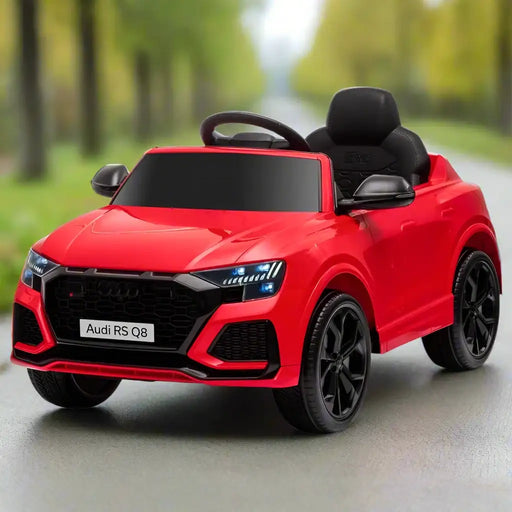 Red Audi RS Q8 kids ride-on car with headlights on, parked on a road outdoors