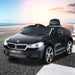 Black BMW 6 GT kids ride-on car toy on outdoor road at sunset