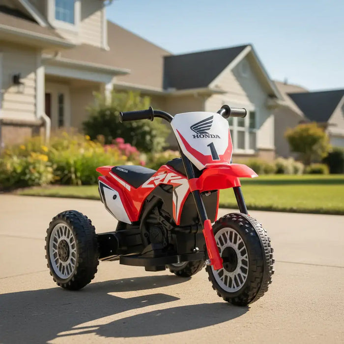 Red Honda kids electric ride-on motorbike on driveway in suburban neighborhood