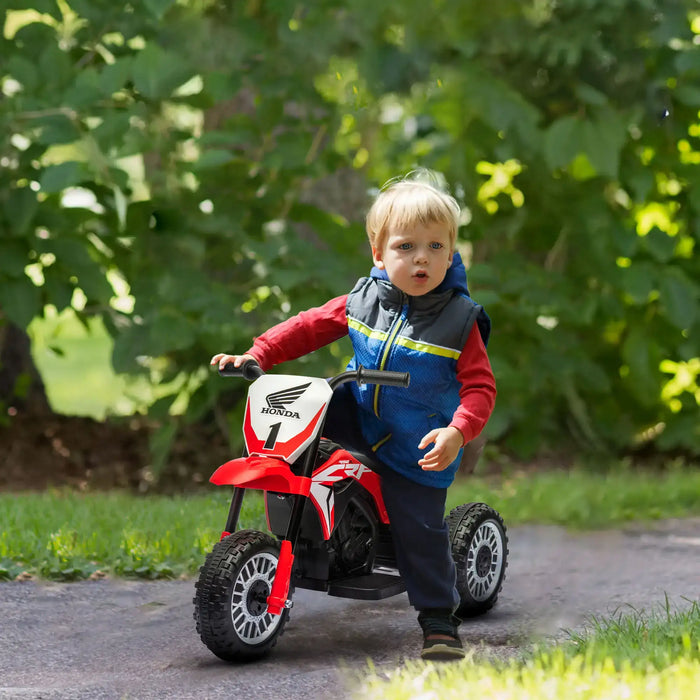 Child riding red Honda CRF450RL kids electric motorbike on outdoor path