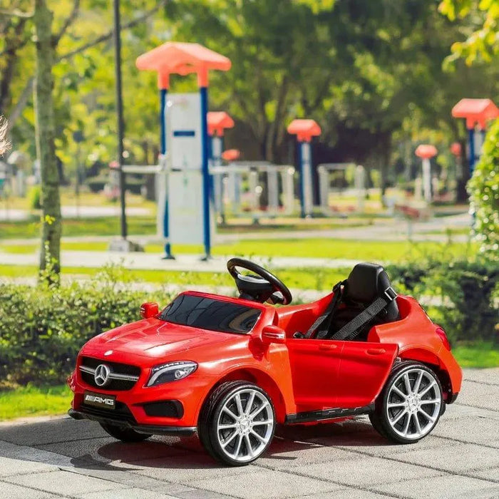 Red Mercedes GLA AMG kids electric ride-on car with open door in a park setting