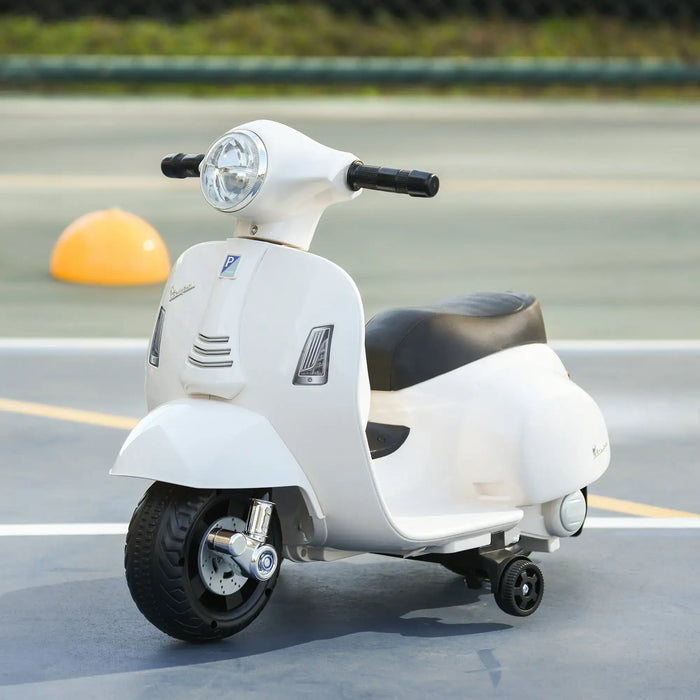 White kids Vespa electric ride-on motorcycle with training wheels on pavement