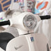White Vespa kids electric ride-on motorcycle close-up with training wheels indoors