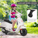 Child wearing pink helmet riding white electric toy scooter with auxiliary training wheels outdoors