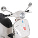 Close-up of white Vespa scooter front with round headlight, chrome mirrors, and black leather seat