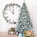 Frosted Christmas tree with decorative items in a room with a large clock.