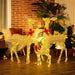 Christmas outdoor decor with three illuminated golden reindeer sculptures wearing red bows on a wooden deck