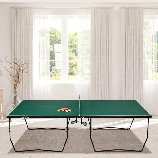 Green 9ft professional table tennis table with paddles, indoor game room setting, sunlight window