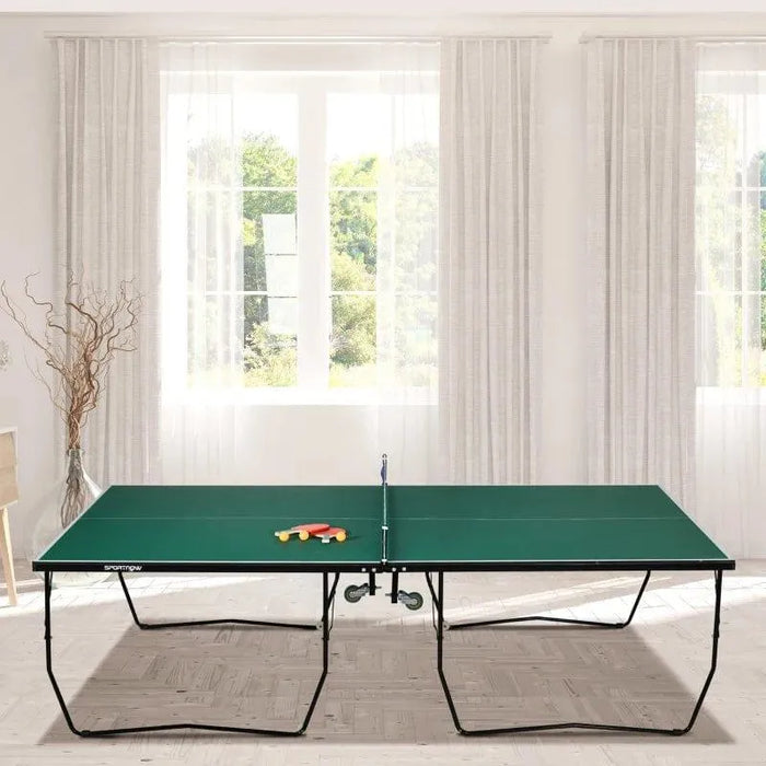 Green 9ft professional table tennis table with paddles, indoor game room setting, sunlight window