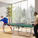 Two men playing table tennis on a green 9ft professional ping pong table indoors