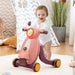 Child playing with a pink scooter toy on a light-colored rug.