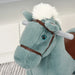 Close-up of a plush blue rocking horse with white mane and brown leather bridle indoors