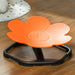 Orange flower-shaped stool on a wooden floor