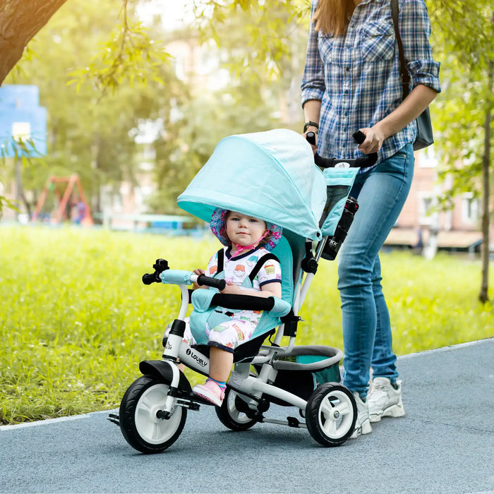 Child in a teal stroller with a hood, being pushed by an adult in a park.
