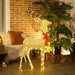 Glowing decorative reindeer with lights and red bow on wooden floor near brick wall and indoor plants