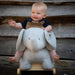 Baby sitting on a plush elephant toy against a wooden background