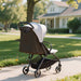 Stroller on a sidewalk with a house and trees in the background