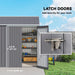 Outdoor gray metal storage shed with latch doors securing garden tools and equipment