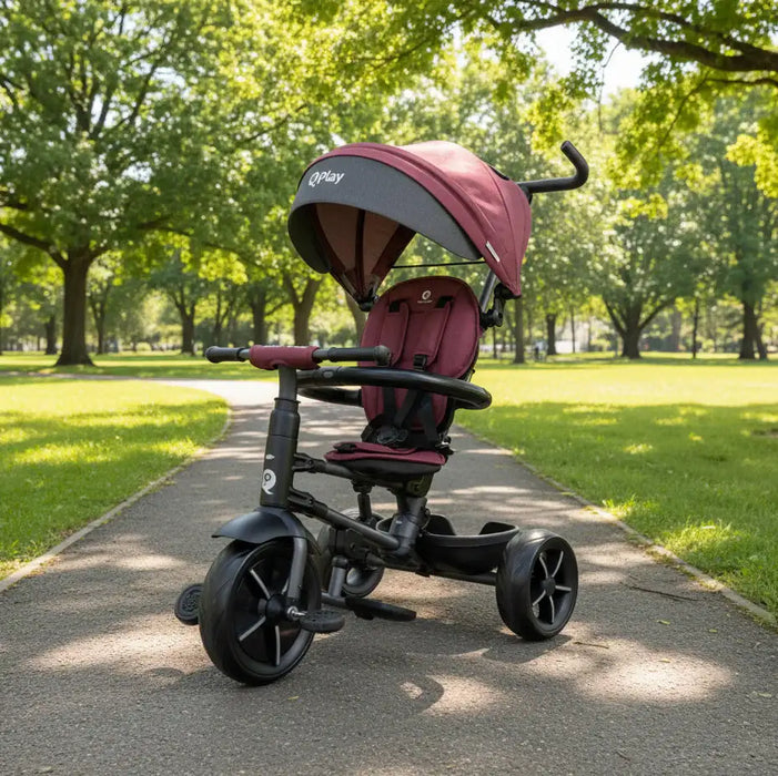 Children's tricycle with a red seat and black frame on a paved path in a park.