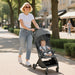 Woman pushing a stroller with a baby on a sidewalk in an urban setting