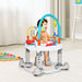Toddler playing in a gray and white baby activity walker with colorful hanging toys in a bright room
