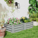 Gray metal raised garden beds with colorful flowering plants in a sunny backyard garden