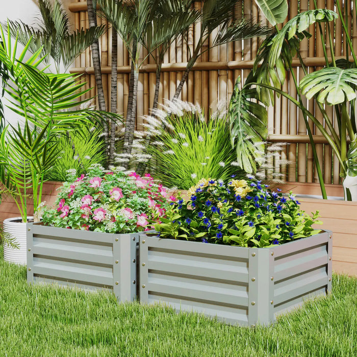 Two grey metal raised garden beds with pink and blue flowering plants in a tropical backyard setting
