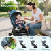 Woman and baby in a stroller with adjustable footrest feature, outdoors.