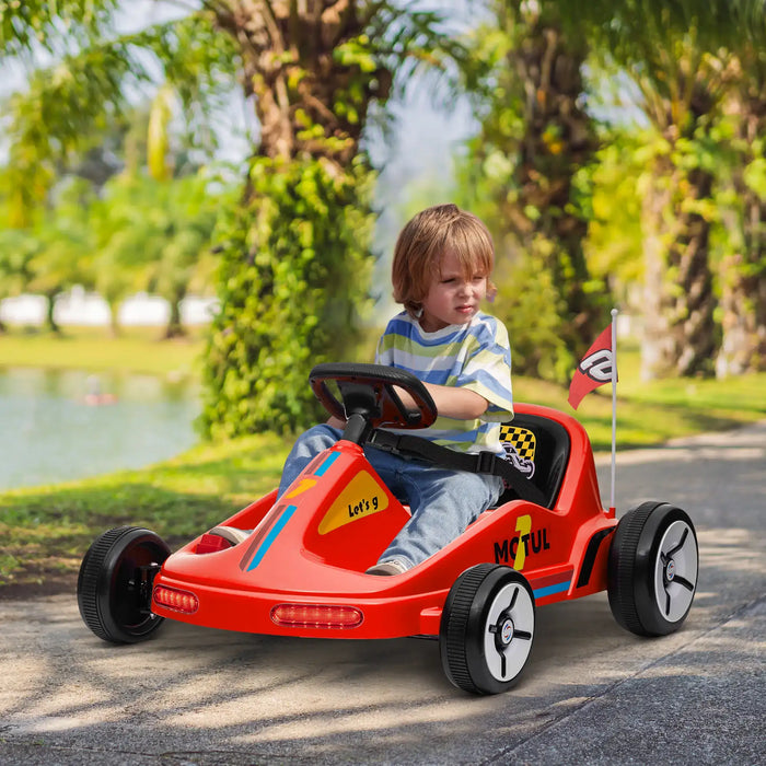 Child driving a red toy car outdoors with greenery in the background