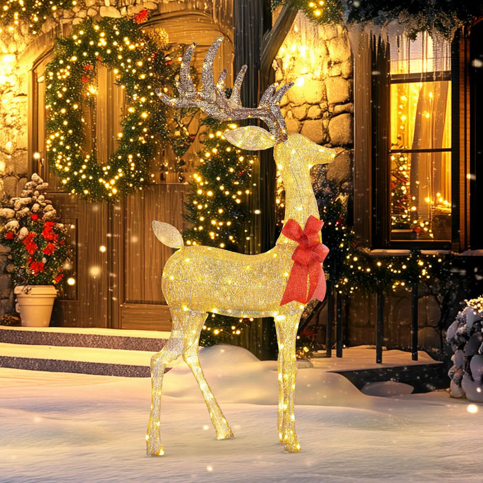 Glowing golden reindeer Christmas decoration with red bow in snowy front yard with wreath and lights