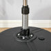 Close-up of black base with metal spring and pipe, floor and gray wall background