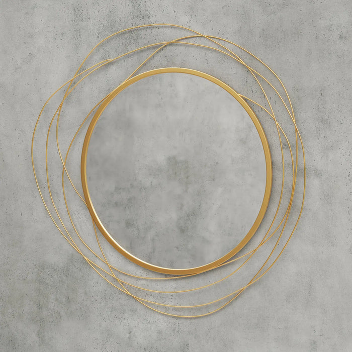 Gold circular mirror with layered design on a gray concrete wall