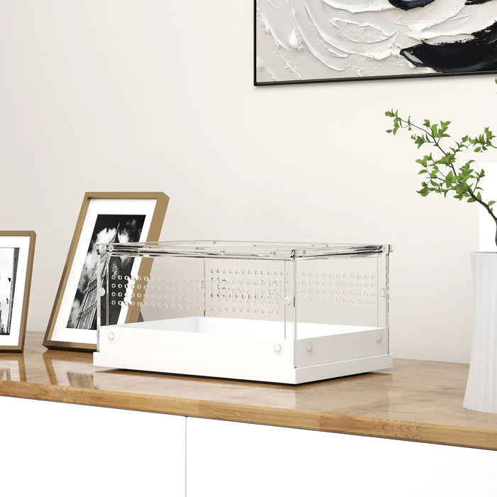 Modern transparent acrylic display case with white base on wooden surface near framed photos and plant